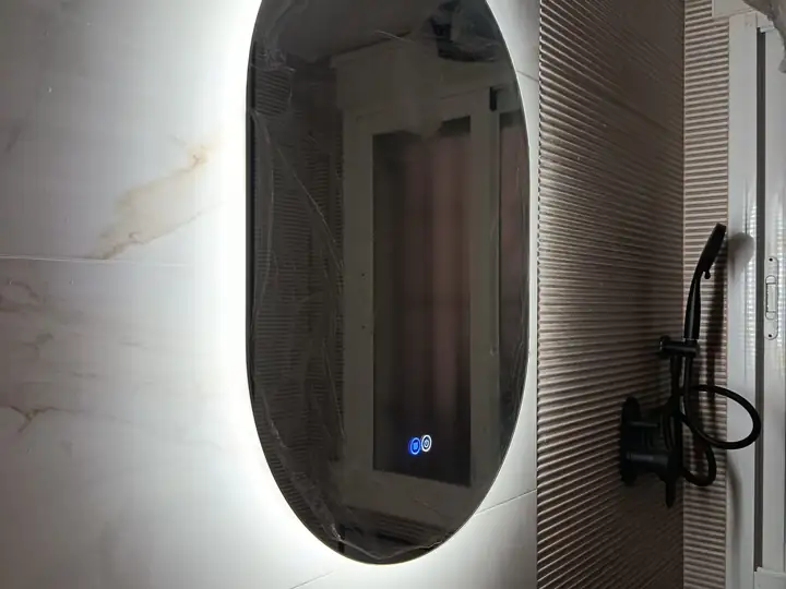 Espejo ovalado retroiluminado con LED y mando táctil instalado en un baño reformado