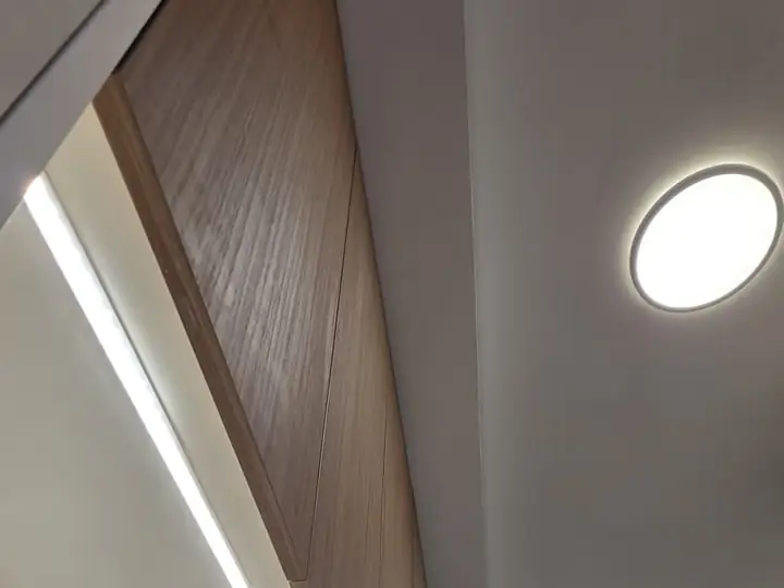 Iluminación LED lineal bajo mueble alto y focos empotrados en el techo de una cocina