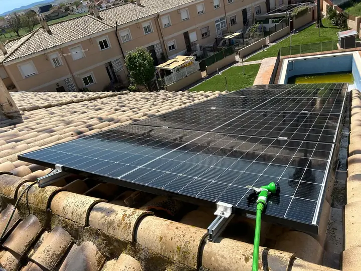 Placas solares instaladas sobre el tejado de teja de una vivienda unifamiliar con piscina